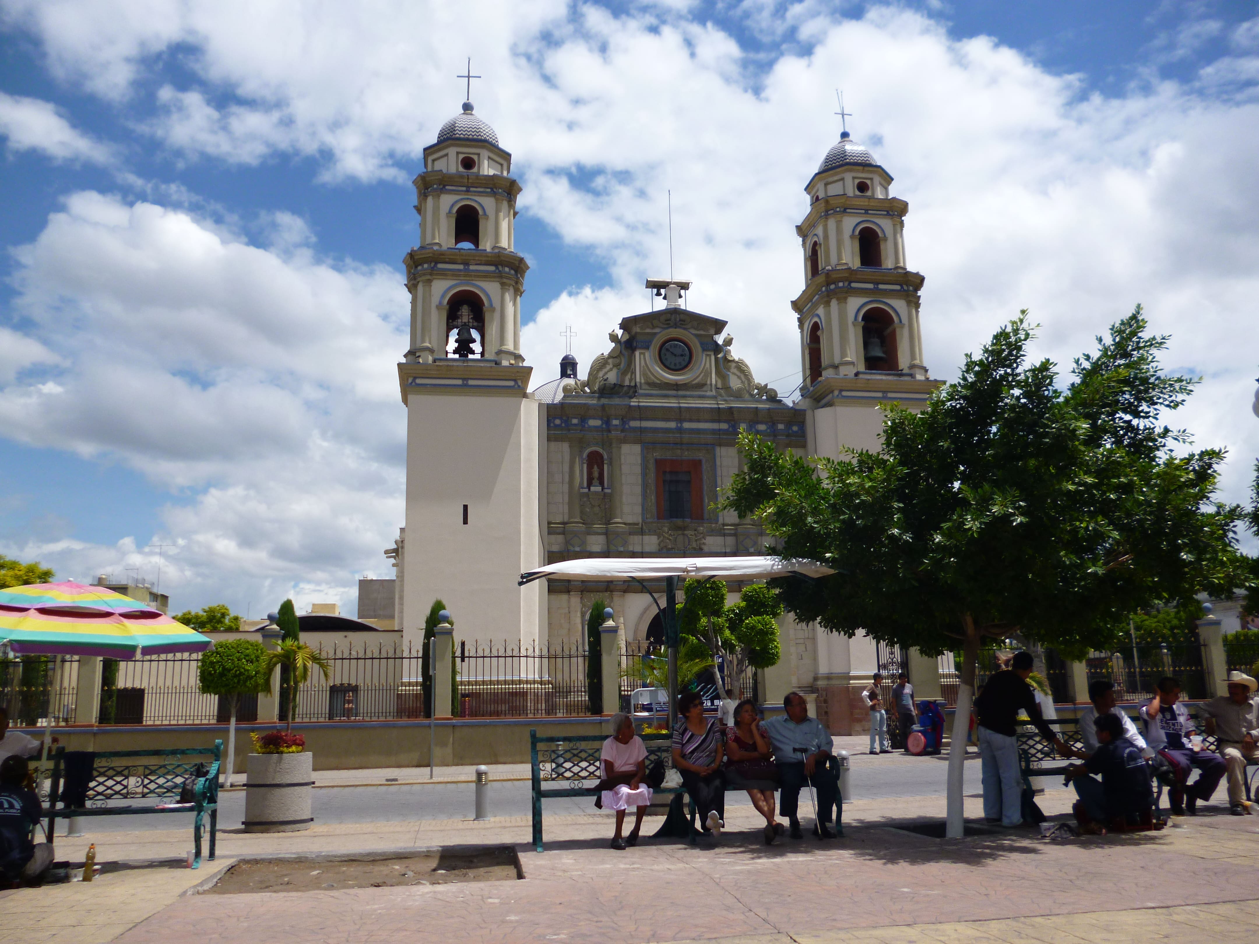 Vista frontal de la Catedral de Tehuacán, Puebla, con personas sentadas al frente
