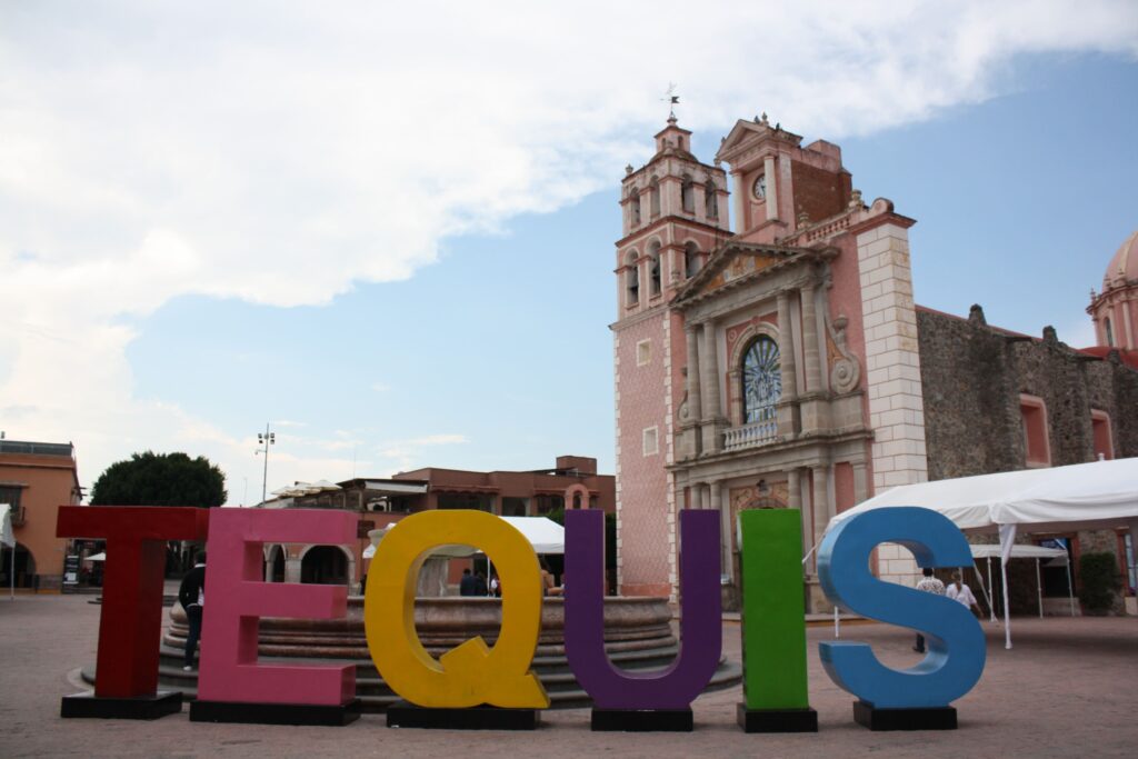 Fotografía del centro de Tequisquiapan con la Parroquia de Santa María de la Asunción al fondo y las letras del municipio al frente. 