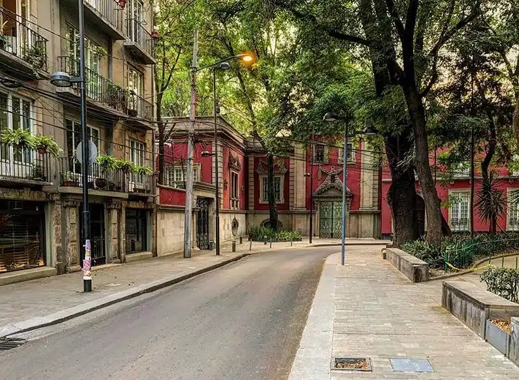 Imagen de una calle de la colonia Roma, en la que se aprecian casas antiguas y un edificio con departamentos en renta.