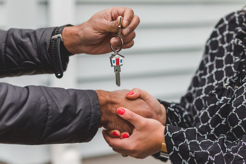 Qué considerar para comprar una casa: agente inmobiliario entregando las llaves de una casa.