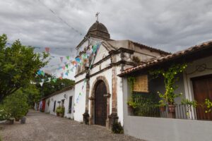 vista lateral de una iglesia y una casa en el municipio. Cerca de este tipo de edificaciones es ideal rentar tu casa en Tlaquiltenango.