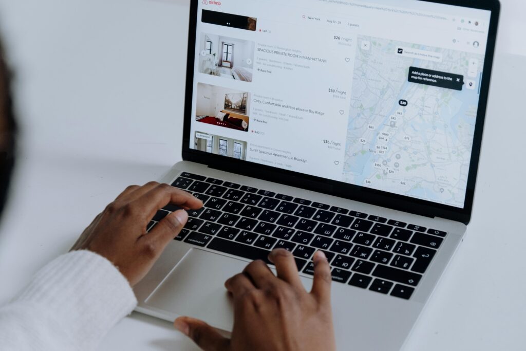 laptop en la plataforma Airbnb, navegando y comprobando las ventajas y desventajas de ser anfitrión Airbnb.