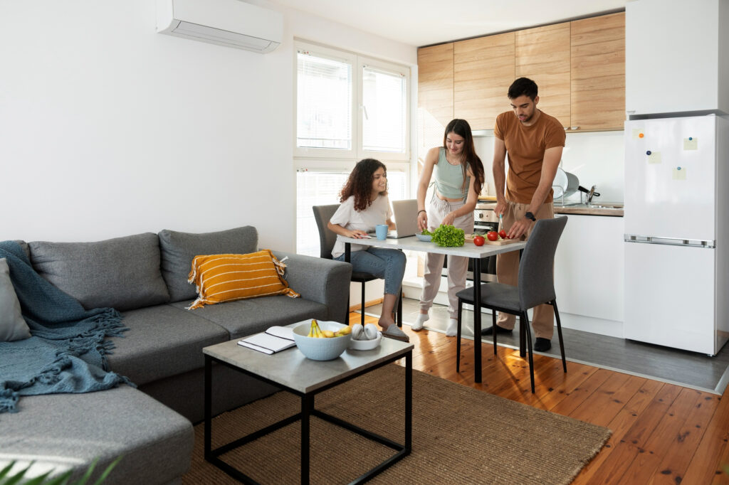 3 jóvenes compartiendo una pequeña mesa en una habitación y preparando comida